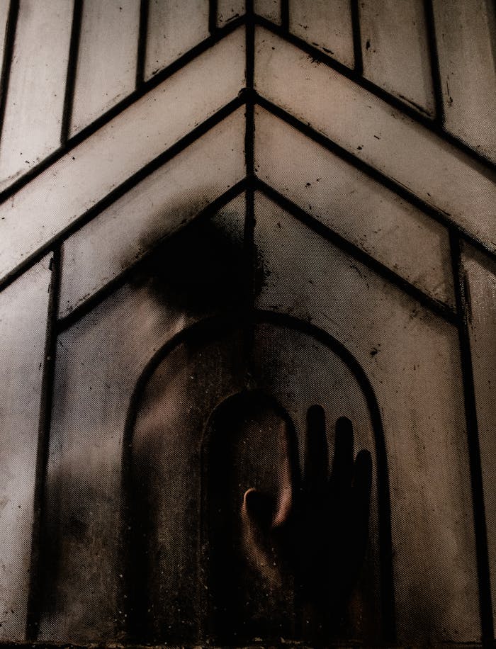 Mysterious silhouette pressing against a frosted window, creating a spooky and eerie atmosphere.